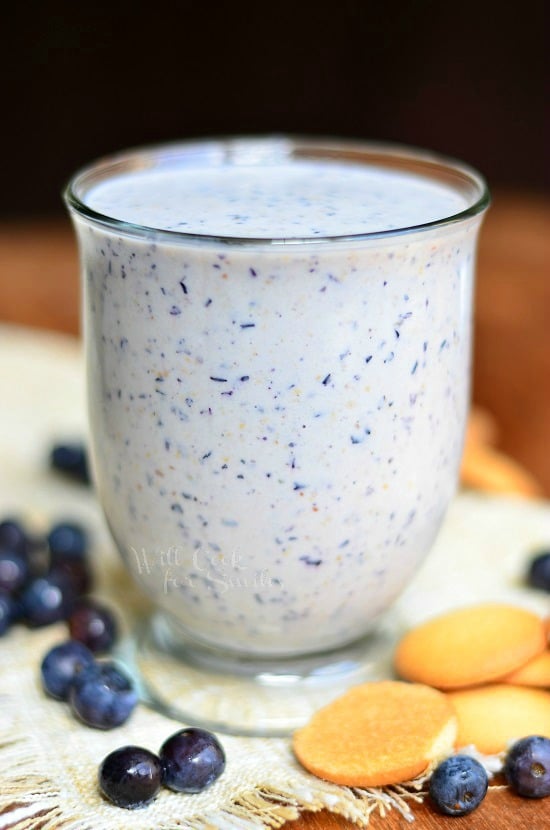 Blueberry Muffin Milkshake in a small clear glass with blueberries around the bottom 