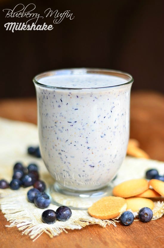 Blueberry Muffin Milkshake in a glass cup with blueberries around it 