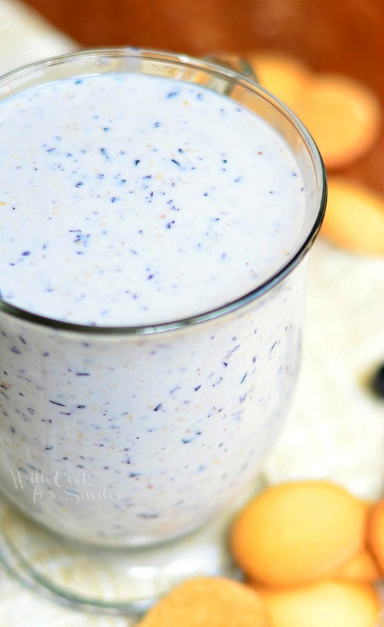 Blueberry Muffin Milkshake in a glass cup with blueberries around it 