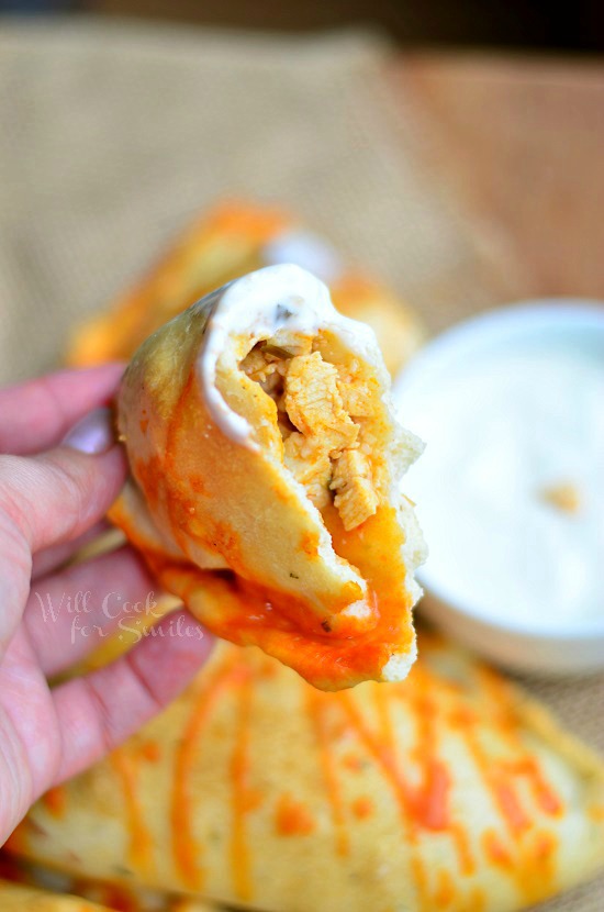 Homemade Buffalo Chicken Calzones with a bite taken out and ranch on it 