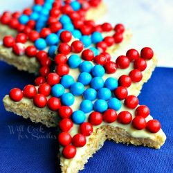 3 candy covered star cookies on a white and blue table cloth