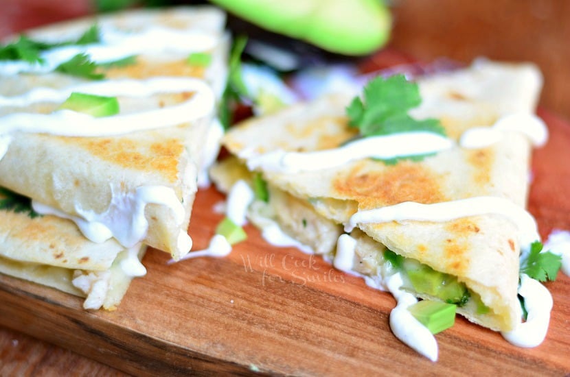 Avocado Chicken Quesadilla sliced up on a wood cutting board 