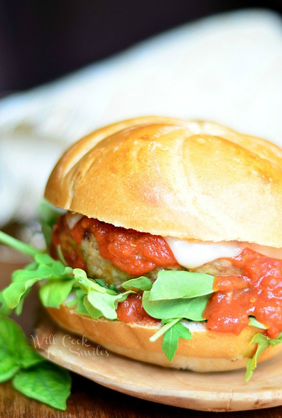 Chicken Parmesan Burger with basil on the bun on a wood cutting board 
