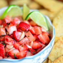 strawberry dessert salsa garnished with lime slices in a white bowl and surounded by chips