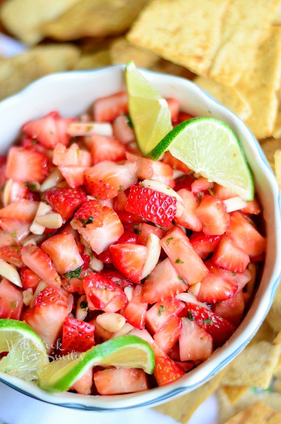 Strawberry Salsa in a bowl with lemon and lime as garnish and chips on the side 