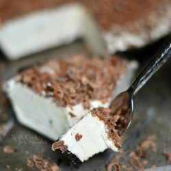 1 slice of Mocha Ice Cream pie on a marble slab cutting board in front of rest of pie with a fork pulling out a portion of pie from slice