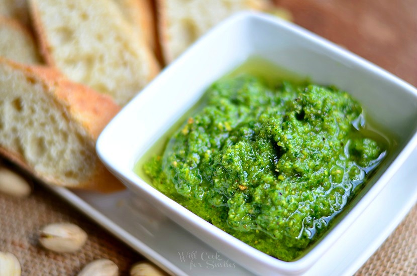 Lemon Pistachio Pesto in a white bowl with some break on a serving plate 