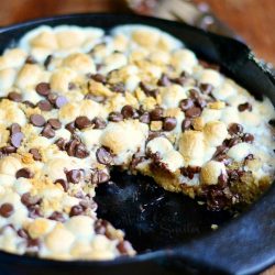 close up view of Smores skillet cookie on wood table with pie cutter to the right resting on table