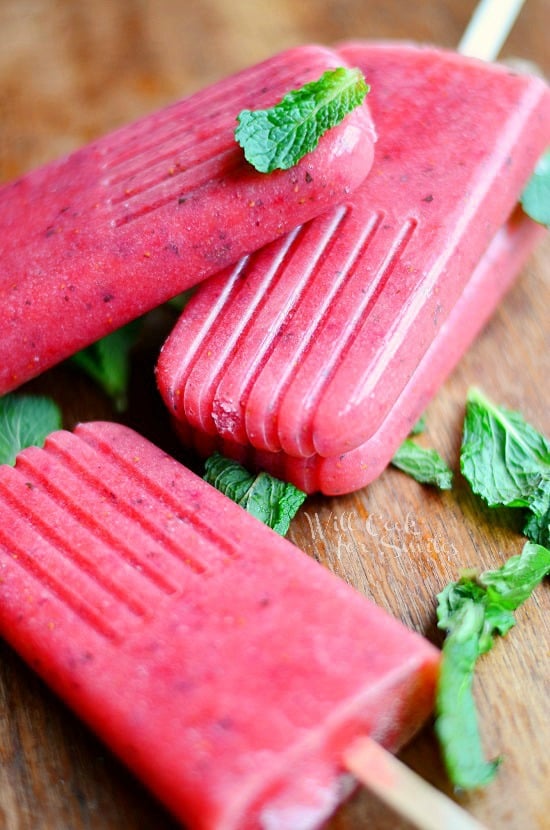 Strawberry Mojito Pops stacked up on a wood board with mint 