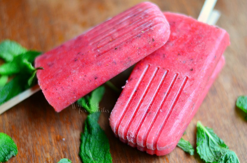Strawberry Mojito Pops  on a wood cutting board with mint all around it 