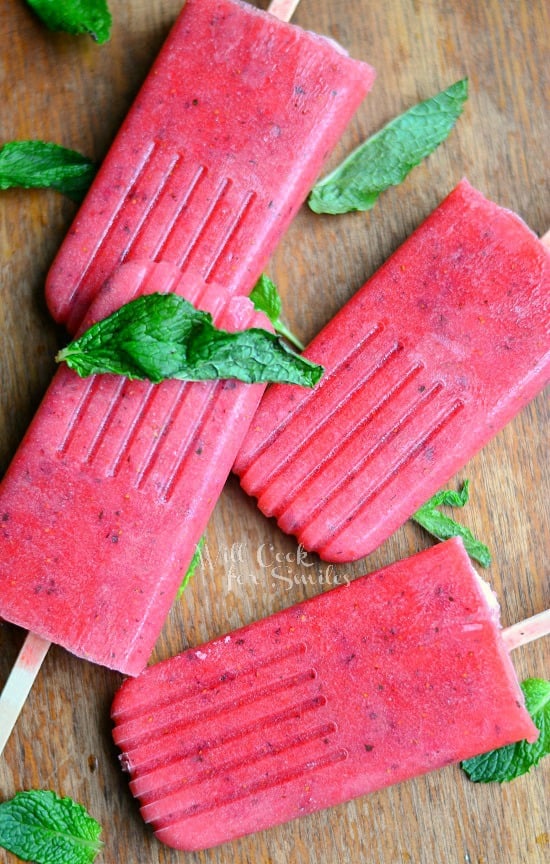 Strawberry Mojito Pops on a wood cutting board with mint around it 