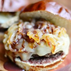 2 buffalo burgers with caramelized onions and demi glace sauce on a wood cutting board