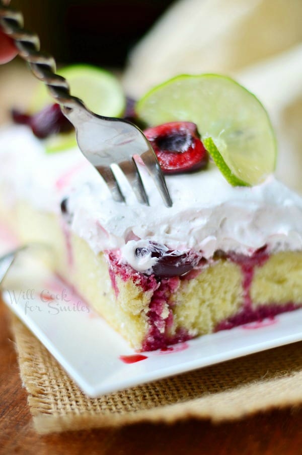 Cherry Limeade Poke Cake on a plate with a fork poking in the cake 