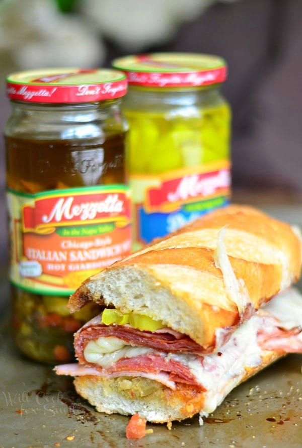 Spicy Baked Italian Sub on a baking sheet with the jars for the peppers behind it 