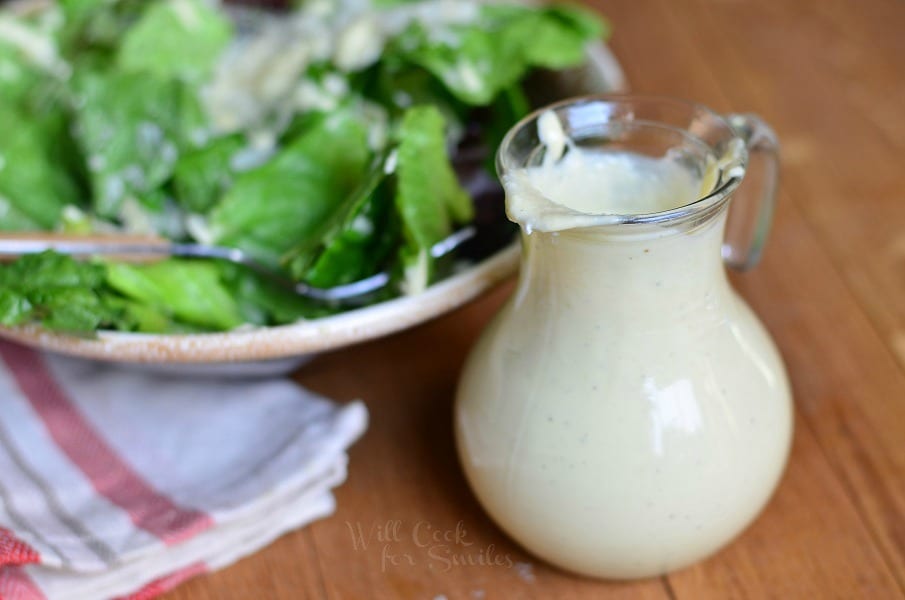 Caesar Dressing in a salad dressing Cruet with salad above it in a bowl 