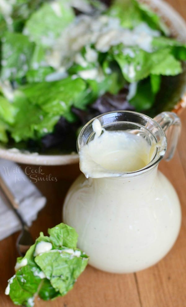 Caesar Dressing in a salad dressing Cruet with salad above it in a bowl 