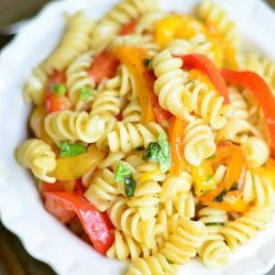 View from above of Roasted Bell Pepper and Garlic pasta salad in a white decorative bowl on a metal baking tray with a fancy fork in front of bowl