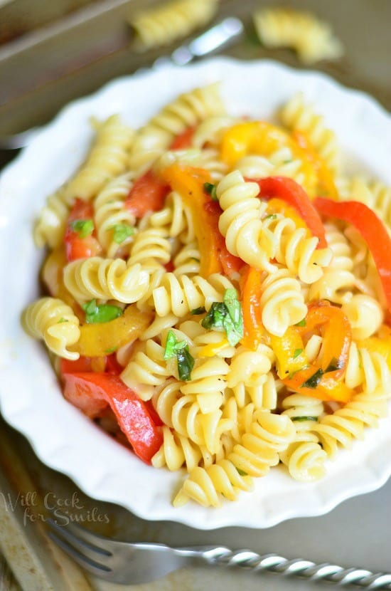 Roasted Bell Pepper and Garlic Pasta Salad wich Basil Dressing in a white bowl with a fork to the left 