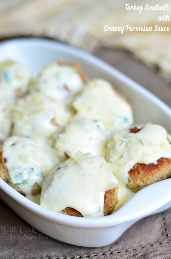 Turkey Meatballs with Creamy Parmesan Sauce over top in a white baking dish 