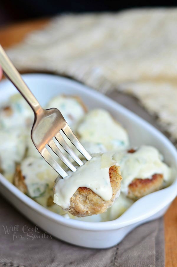 Turkey Meatballs with Creamy Parmesan Sauce in a casserole dish with a fork lifting one out 