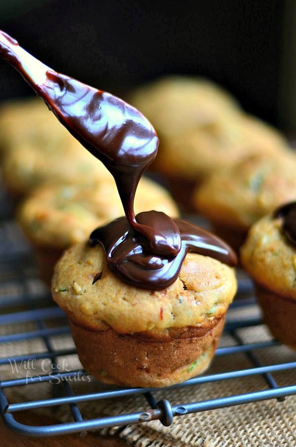 Zucchini Muffins with Hot Fudge Sauce being poured over it with small white spoon 
