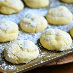 side view of banana pudding chewy cookies in baking tray on wood table covered in powdered sugar