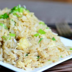 close up view of white rectangle plate with crab fried rice all on a bamboo placemat