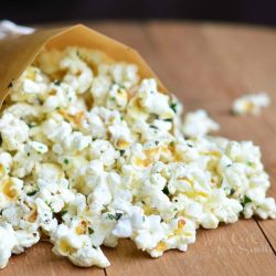 close up view of wax paper rolled into cup holding a heaping portion of Italian Truffle oil popcorn on a wood table