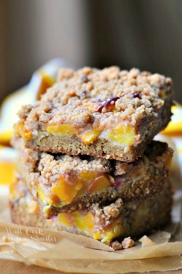 Peach Crumble Cookie Bars stacked up on parchment paper 