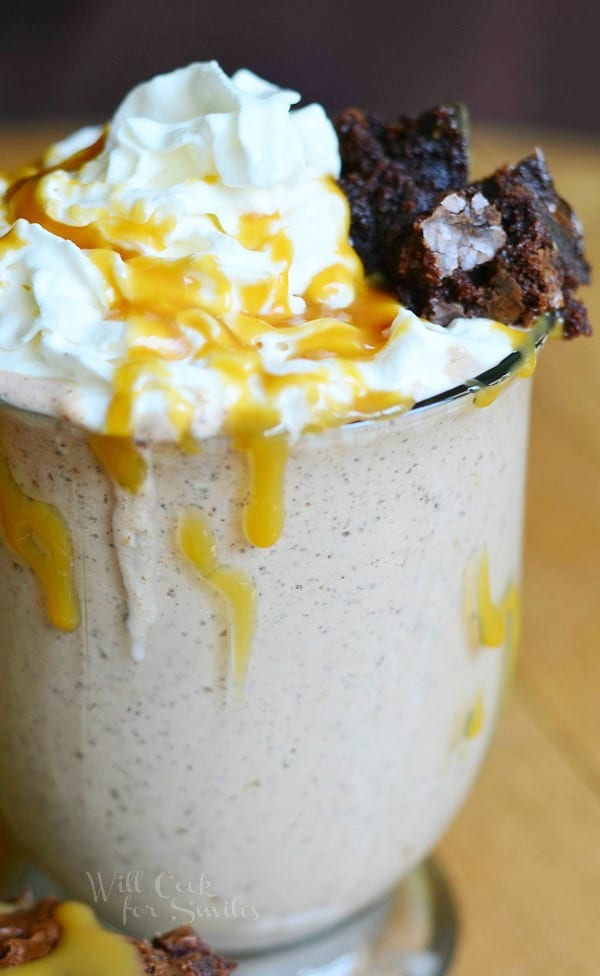 Salted Caramel Brownie Milkshake in a glass with whipped cream, caramel on top with a brownie 