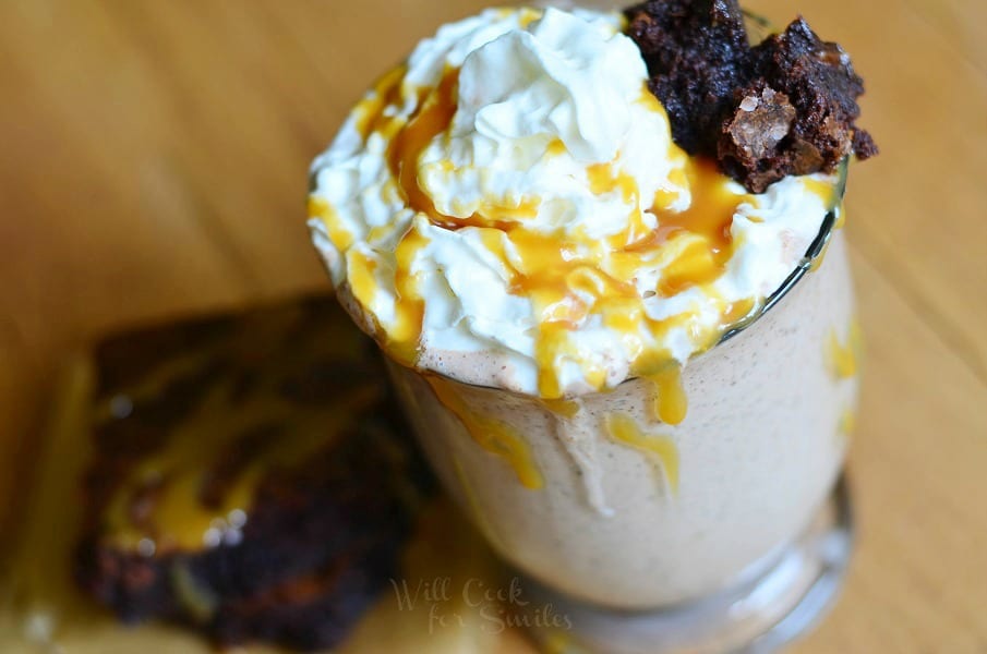 Salted Caramel Brownie Milkshake in a glass with whipped cream, caramel on top with a brownie 