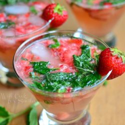 view from above and close up of 3 short stem martini glasses filled with skinny strawberry mojito on a wooden table with each glass topped with a strawberry garnish and mint