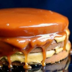 Close up view of Whole caramel cake on a black cake presenter with a black background
