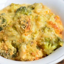 closeup of cheesy broccoli casserole in a white bowl.