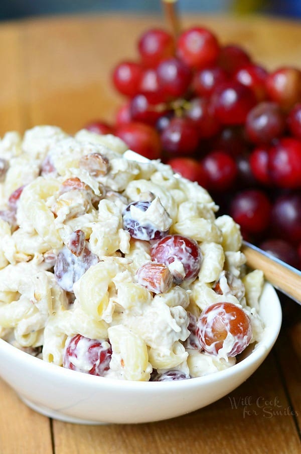 chicken salad with macaroni and grapes in a bowl on a table with grapes 