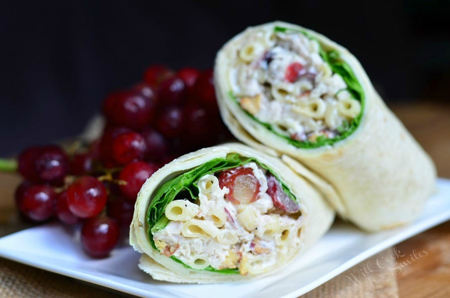 Chicken Salad with Macaroni and Grapes in a wrap on a white plate with grapes on a woven placemat 