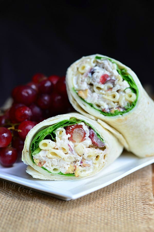 Chicken Salad with Macaroni and Grapes in a wrap on a white plate with grapes on a woven placemat 