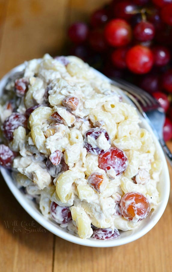 chicken salad with grapes in a serving bowl with grapes on a wood table with a fork