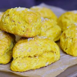 8 savory three cheese cream cheese scones on a piece of wax paper on a wooden table