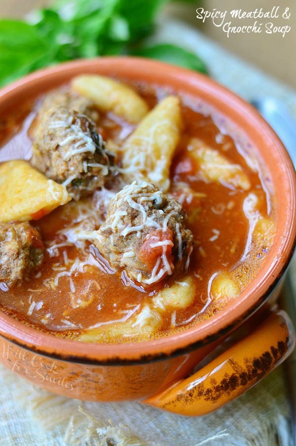 Spicy Meatball & Gnocchi Soup in an orange bowl. Tomato based soup with meatballs, gnocchi, and grated Parmesan cheese on top.