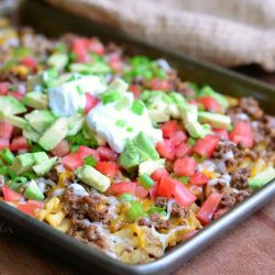 small baking tray with Taco Waffle nachos on a wood table with a brown cloth in the background