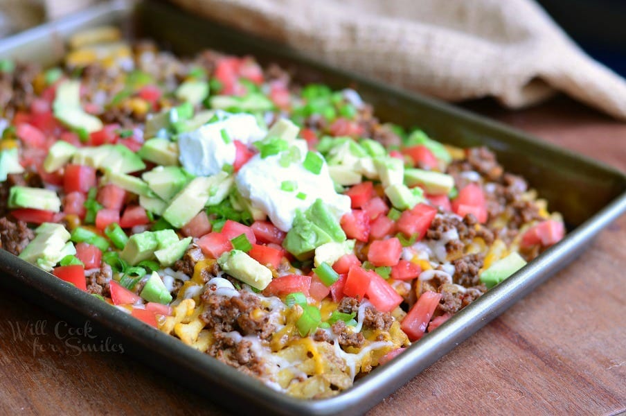 Taco Loaded Fries Nachos. Crispy baked waffles fries loaded with taco beef, tomatoes, avocado green onions and cheese. #appetizer #snack #taco #groundbeef #nachos