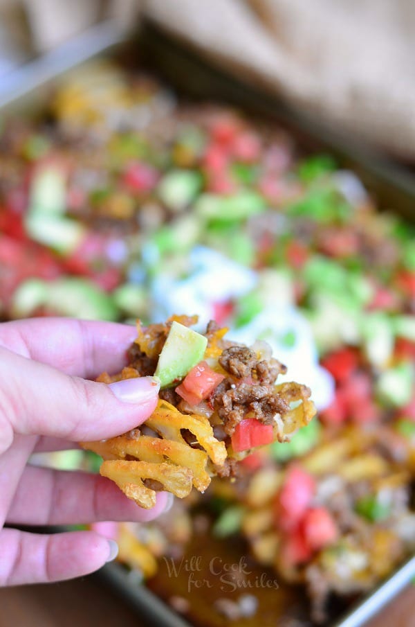 Taco Loaded Fries Nachos. Crispy baked waffles fries loaded with taco beef, tomatoes, avocado green onions and cheese. #appetizer #snack #taco #groundbeef #nachos