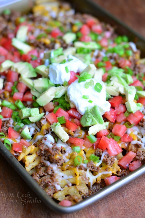 Taco Loaded Fries. Crispy baked waffles fries loaded with taco beef, tomatoes, avocado green onions and cheese. #appetizer #snack #taco #groundbeef #nachos