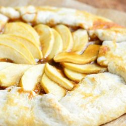 close up view of caramel apple galette on wax paper on wooden table