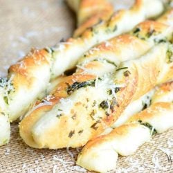 close up view of homemade paresan garlic herb breadsticks on a tan placemat