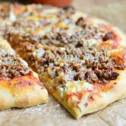 close up view of lasagna pizza on wax paper with one slice pulled from pizza pie