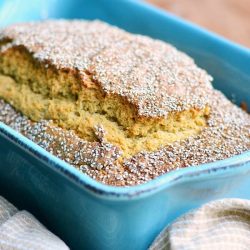 baked vanilla chai tea bread in a blue baking dish on a wooden table with a tan cloth below