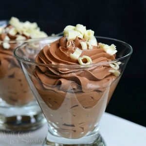 dessert glass filled with chocolate mousse on a white rectangular plate with additional glass and mousse in background