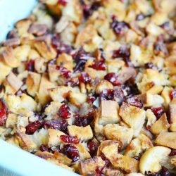 Blue baking dish with cranberry pecan stuffing on a tan placemat